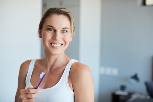 Cropped portrait of an attractive young woman holding a toothbrush at home