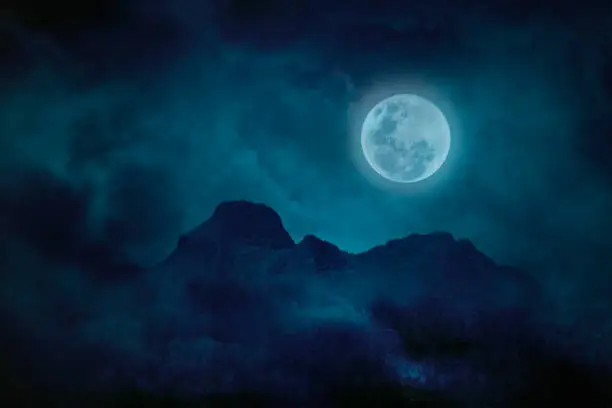 Photo of Blue full moon with mountains and forests in the darkness, Natural scary background