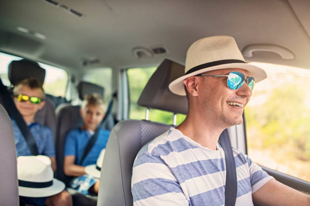 Father driving a car on a road trip Father driving a car on a road trip. Two boys visible in the back seat.
Sunny summer day.
Nikon D850 family-van-driving stock pictures, royalty-free photos & images