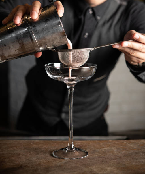 istock bartender pouring cocktail shaker and strainer to glass on bar counter 1155147669