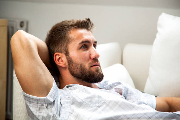 istock Attractive man with a beard is relaxing on a couch 1155152554