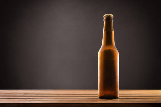 istock Beer bottle filled and closed on wood table black background. 1155163383