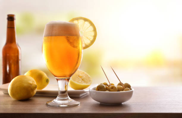 Glass of beer with lemon with appetizer on wooden table stock photo