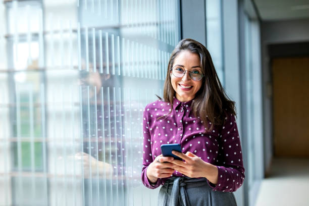 istock Smiling woman with a phone in office 1155164142