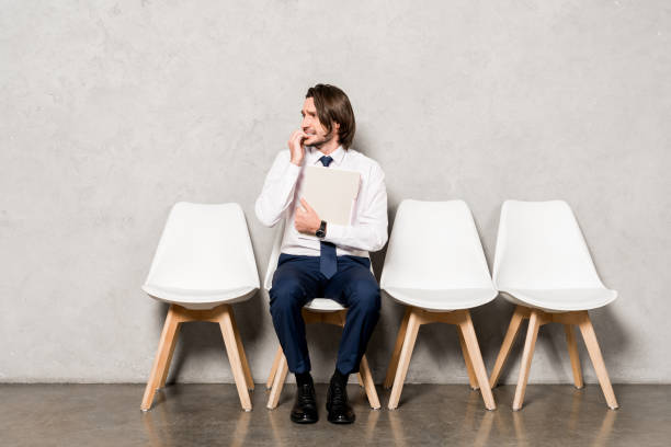 istock worried man in formal wear holding folder while waiting job interview 1155165244