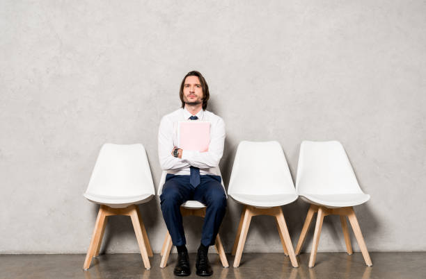 istock handsome man sitting on chair with crossed arms and holding folder 1155165245