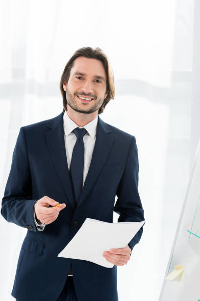 istock handsome man smiling while holding paper and pencil in hands 1155165327