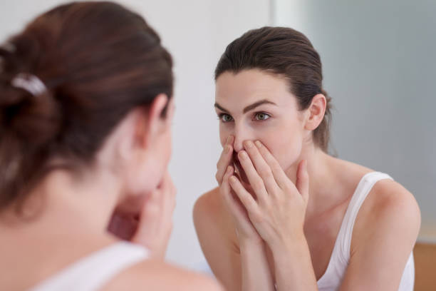 Keeping the health of her skin in check Shot of an attractive young woman inspecting her face in the bathroom mirror caucasian appearance stock pictures, royalty-free photos & images