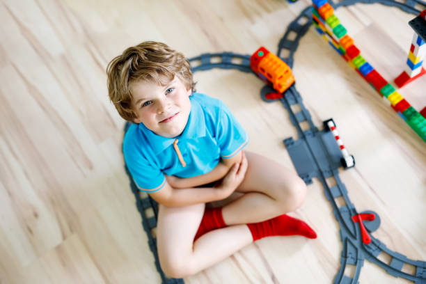 istock little blond kid boy playing with colorful plastic blocks and creating train station 1155168289