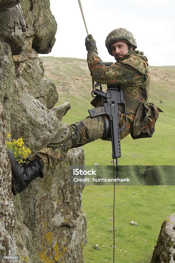 Вооруженных военных альпинист hanging on rope - Стоковые фото Альпинизм роялти-фри
