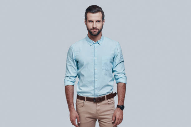 istock Charming man. Handsome young man looking at camera and smiling while standing against grey background 1155172951