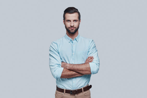 istock Perfect man. Handsome young man looking at camera and smiling while standing against grey background 1155173029