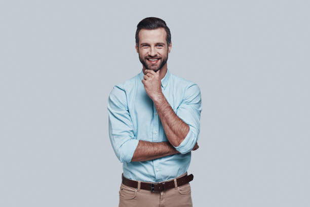 istock Portrait of confidence. Handsome young man looking at camera and smiling while standing against grey background 1155173085