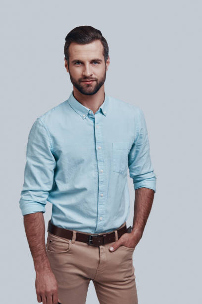 istock Pure confidence. Handsome young man looking at camera and smiling while standing against grey background 1155173896