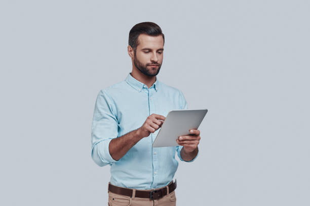 istock Planning new business. Handsome young man using digital tablet while standing against grey background 1155175751