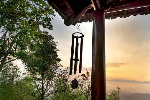 a wind chime hanging from the edge of a temple roof.