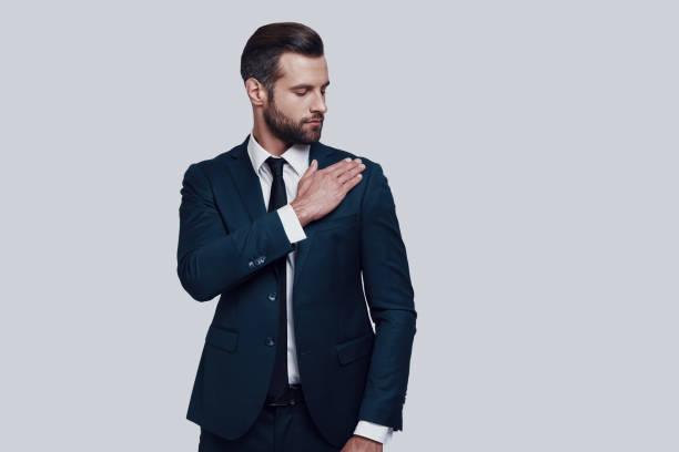 istock Everything must be perfect. Handsome young man cleaning jacket while standing against grey background 1155177527