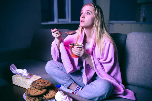 filme de observação da mulher nova na noite. comendo o gelado ou o chocolate com colher. bolinhos na tabela. streaming show na tv. - cookie women eating beautiful - fotografias e filmes do acervo