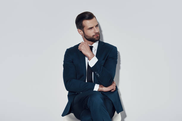 istock Taking time to think. Handsome young man looking away while sitting against grey background 1155178744