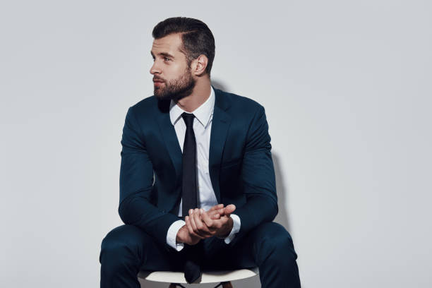 istock What to do? Handsome young man looking away while sitting against grey background 1155179152