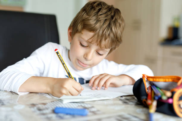 istock Tired kid boy at home making homework writing letters with colorful pens 1155181814