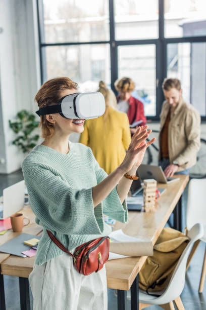 istock smiling female designer gesturing with hands while having virtual reality experience in loft office with colleagues on background 1155182081