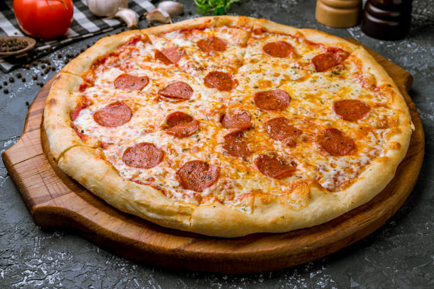 istock Pepperoni pizza on board on wooden background 1155182399