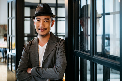 Fashionable Asian man with arms crossed, looking cheerfully at camera, confidence, freelance work