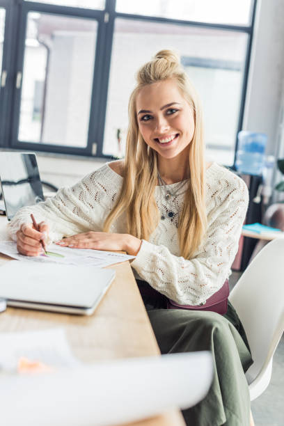 istock beautiful female architect looking at camera  and working on blueprint in loft office 1155183732