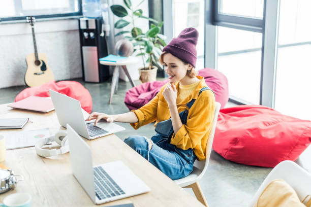 istock beautiful smiling young female it specialist using laptop in loft office 1155183763