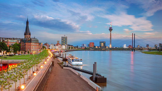Panoramic cityscape image of riverside Düsseldorf, Germany with Rhine river during sunset.