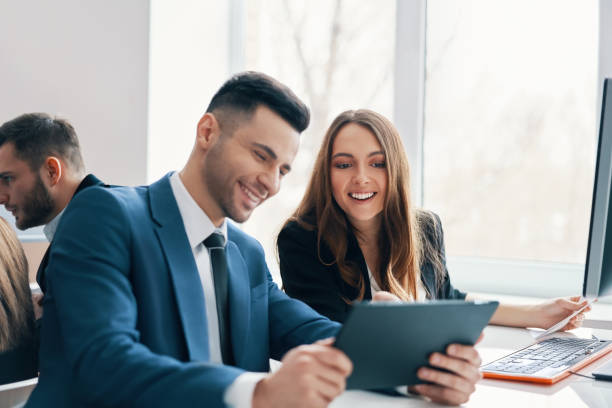 istock Smiling successful business people discussing ideas using digital tablet in office 1155186506