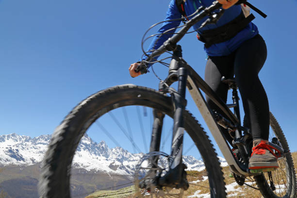istock Female mountain biker descends grassy hill 1155187567