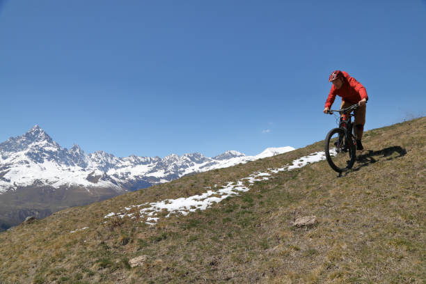 istock Male mountain biker descends grassy hill 1155187739
