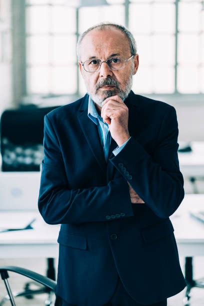 istock Senior businessman standing in modern workplace 1155188217
