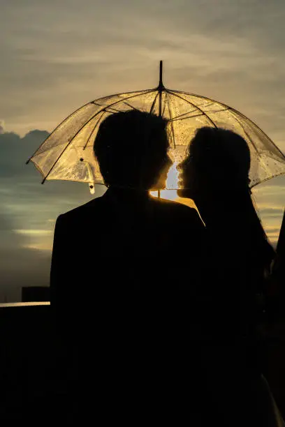 Silhouette couple prewedding under umbrella at sunset