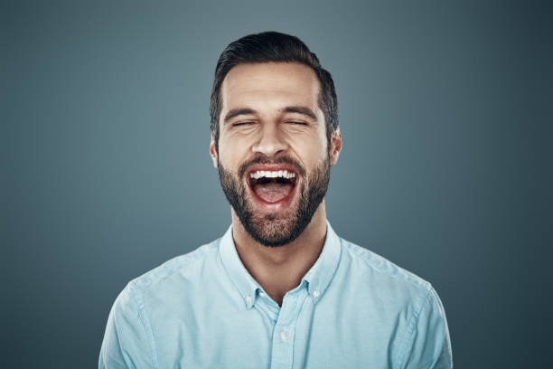 istock So much fun! Handsome young man laughing while standing against grey background 1155191452