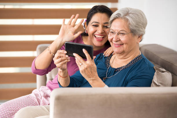 istock Woman with senior mother using mobile phone for video chat 1155194880