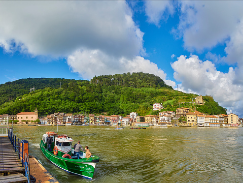 Pasajes de San Juan (Pasai Donibane), Spain - June 5, 2019. Fishing village of Pasajes de San Juan on a sunny day with the Boat crossing service docking in foreground. Gipuzkoa, Basque country, Spain.