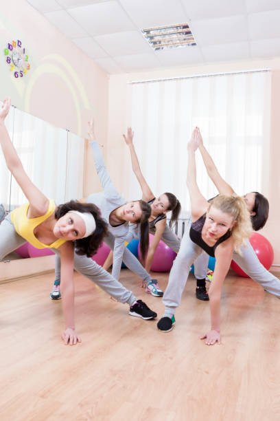 istock Group of Five Professional Sportswomen Making Stretching Exercises with Trunk Bending in Sport Class. Vertical Shot 1155199645