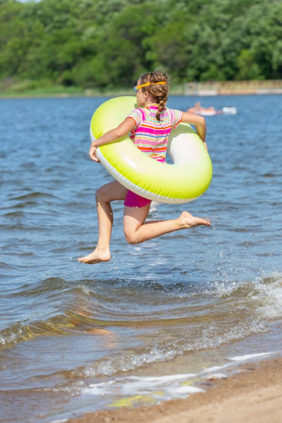 istock Girl Jumping Into Water With Inner Tube 1155201378