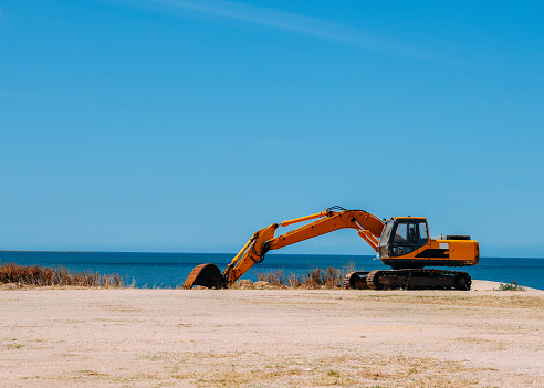 Yellow bulldozer working on a beach with copy space.