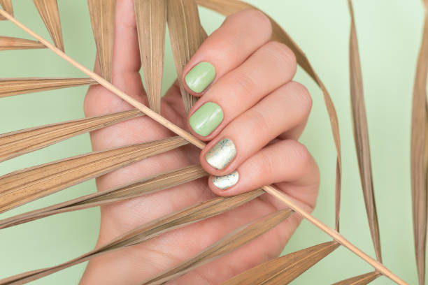 istock Female hand with green nail design. 1155203377