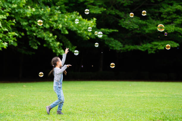 istock Girl playing with soap bubbles 1155203903