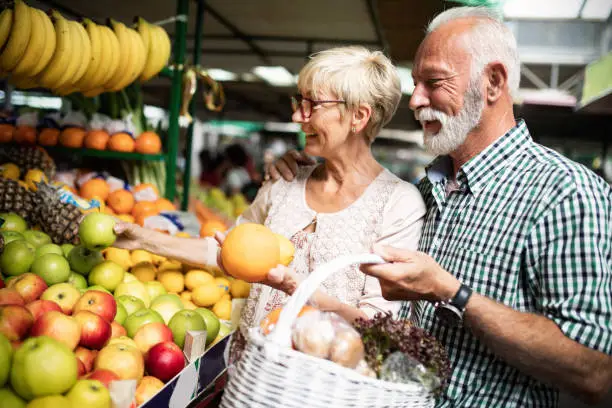 Senior couple choosing bio food fruit and vegetable on the market during weekly shopping