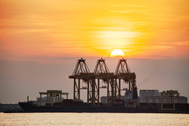istock Crane for shipping container carrier with sunrise background 1155210751