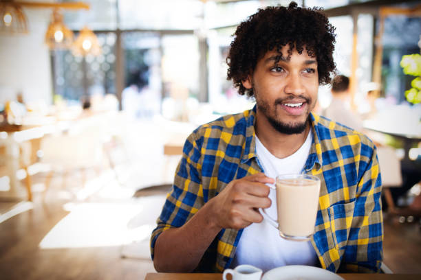 istock Handsome young african man drinking a cup of coffee at an cafe 1155211841