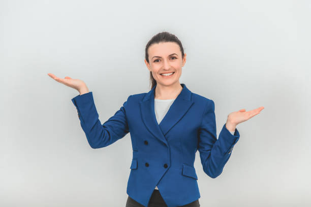istock Beautiful teacher standing, raising her hands, holding palms opened for some product, smiling lovely. 1155212819
