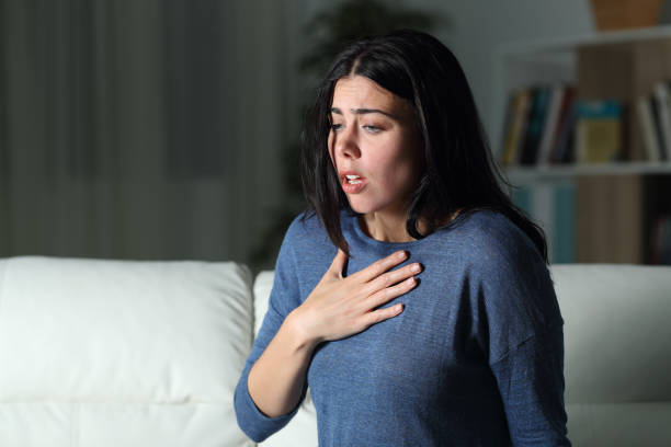 donna che soffre di un attacco d'ansia da sola nella notte - asthmatic foto e immagini stock