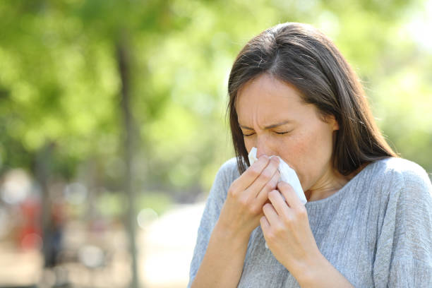 istock Woman sneezing using a wipe in a park 1155214687